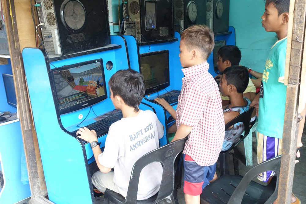 ネットカフェでゲームをする子供たち。